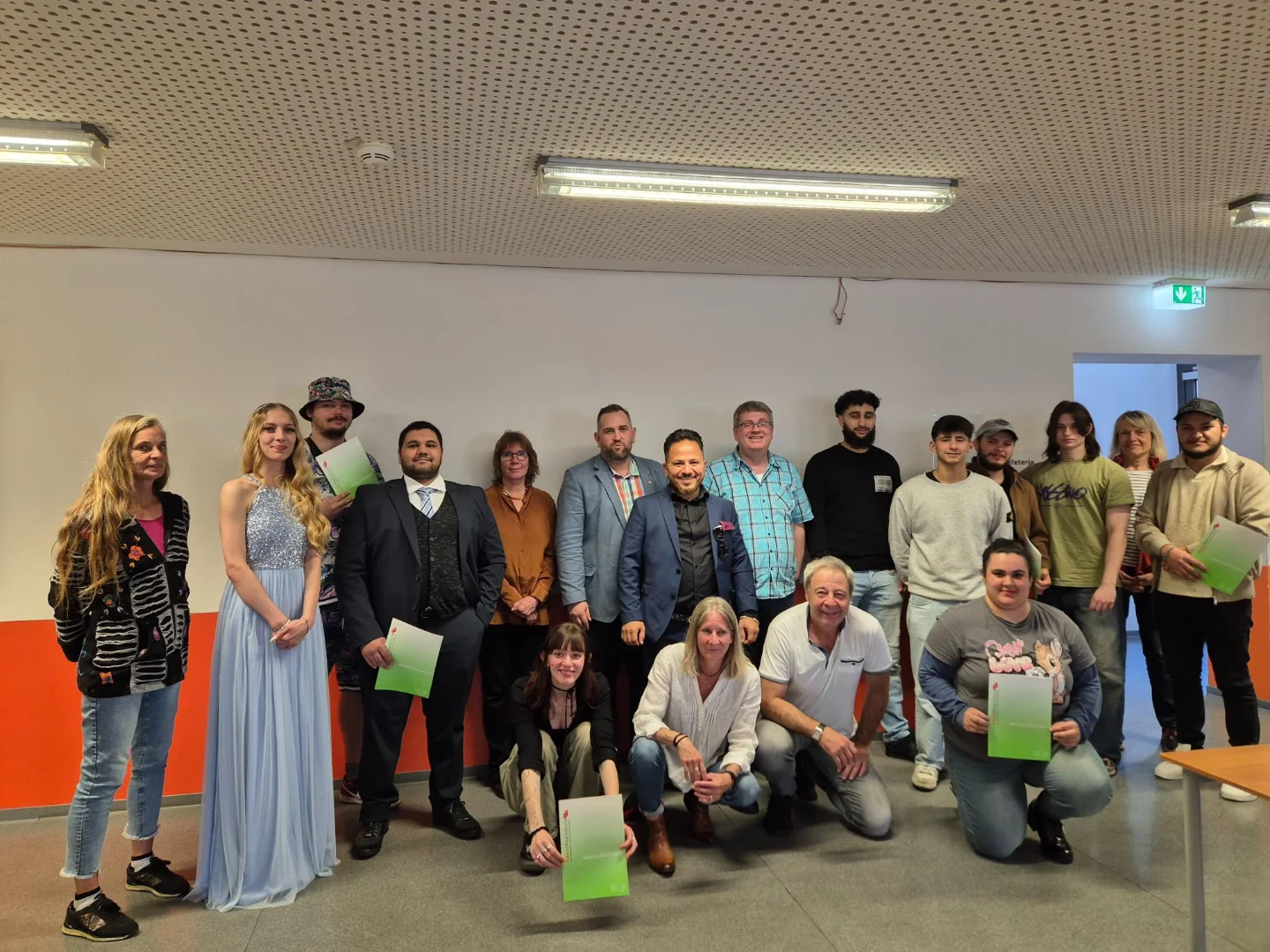 Gruppenfoto der Absolventinnen und Absolventen, die nach bestandenem Abschluss ihre Zeugnisse in die Kamera halten.