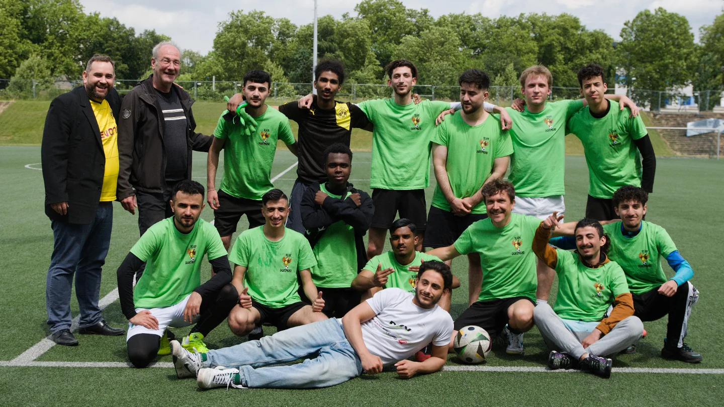 Das Fußballteam der Abendrealschule posiert für ein Mannschaftsfoto auf dem Spielfeld.