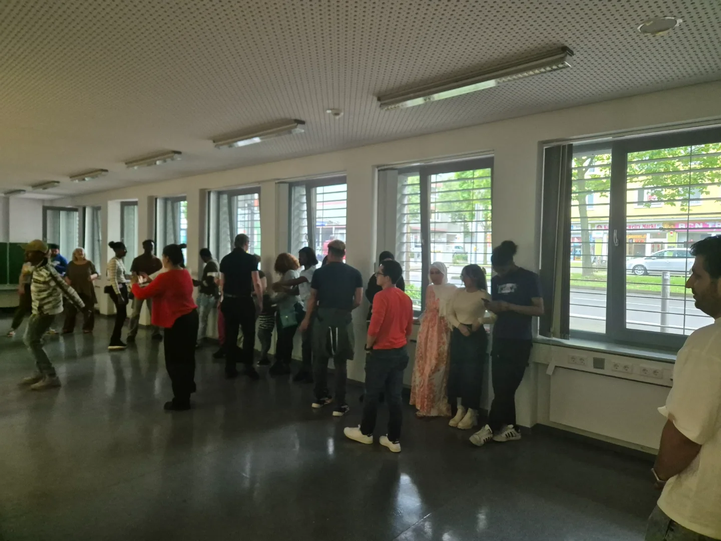 Eine Gruppe von Gästen und Studierenden steht in einem Raum für eine gemeinsame Aktivität zusammen.